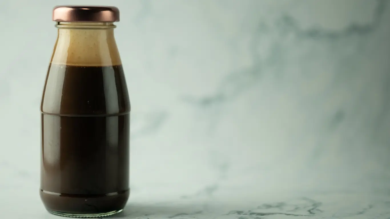 Amber glass cold brew coffee bottle with a secure black screw closure for UV light protection.