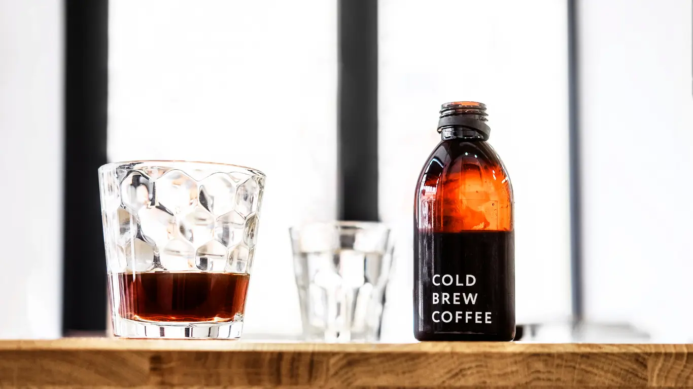 Clear glass beverage packaging containers displaying filled cold brew coffee and iced latte presentation.