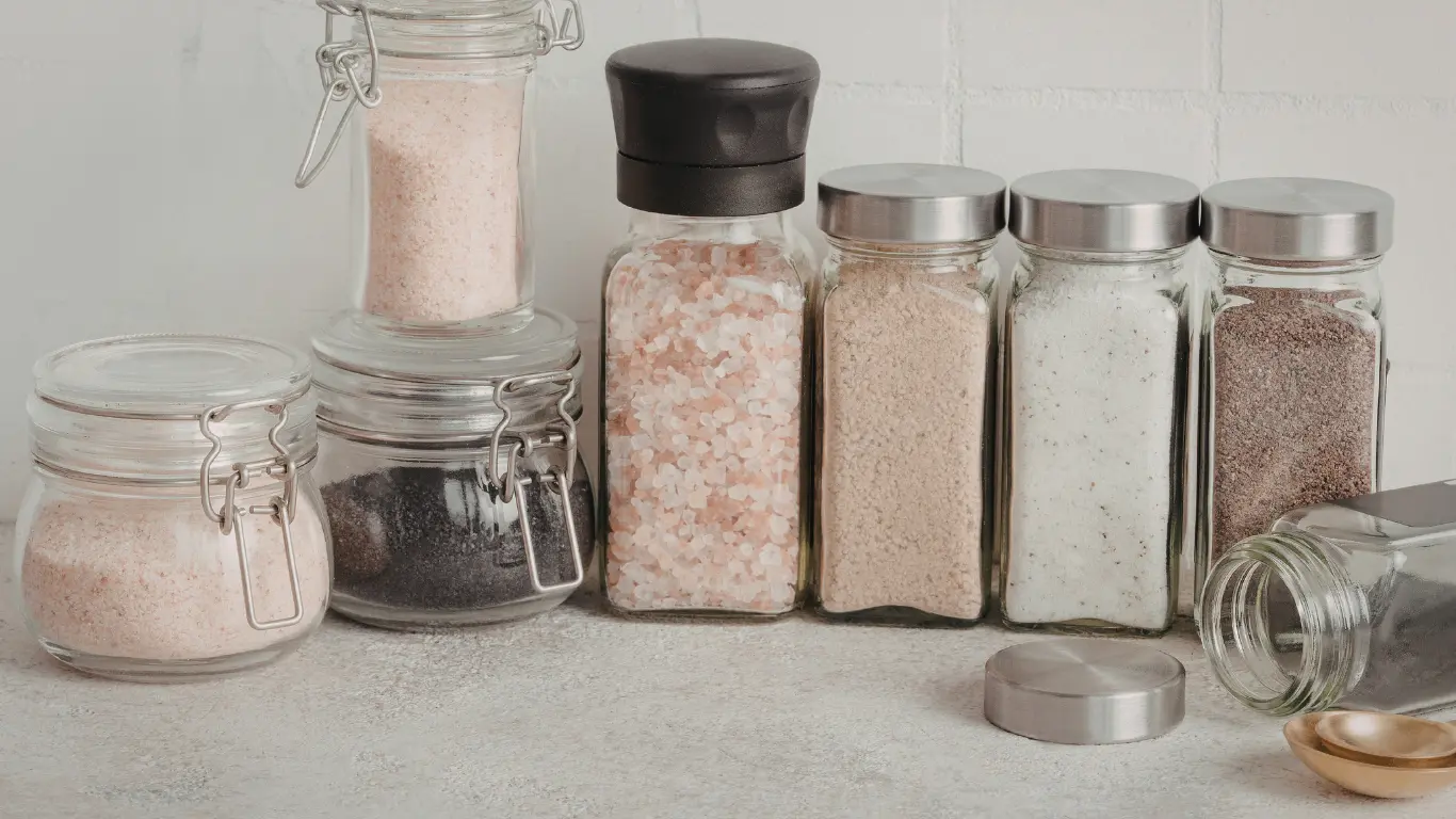 Industrial seasoning containers including wire-bale glass jars and spice shaker bottles with stainless steel caps.