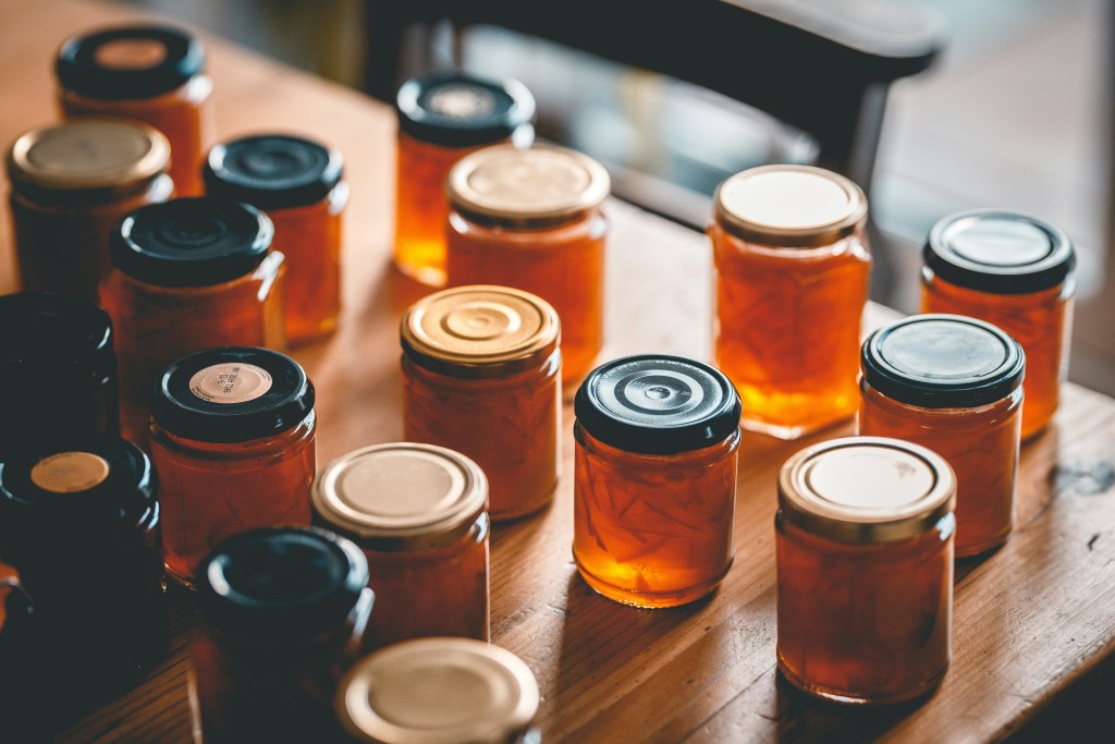 Assortment of glass jam jars filled with orange preserves on a rustic wooden table