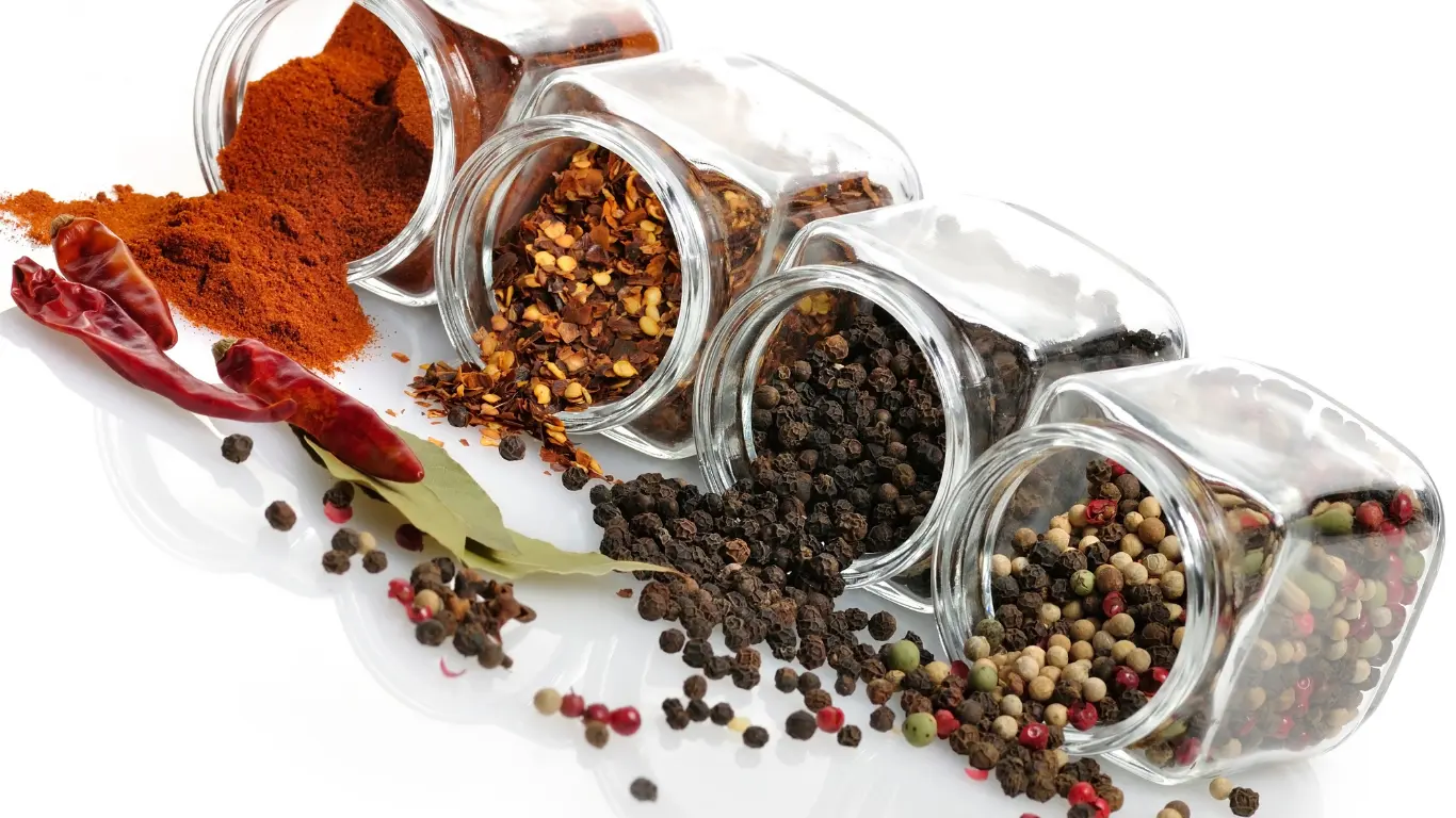 Bulk round glass seasoning jars pouring dry spices and black pepper for retail food brands.