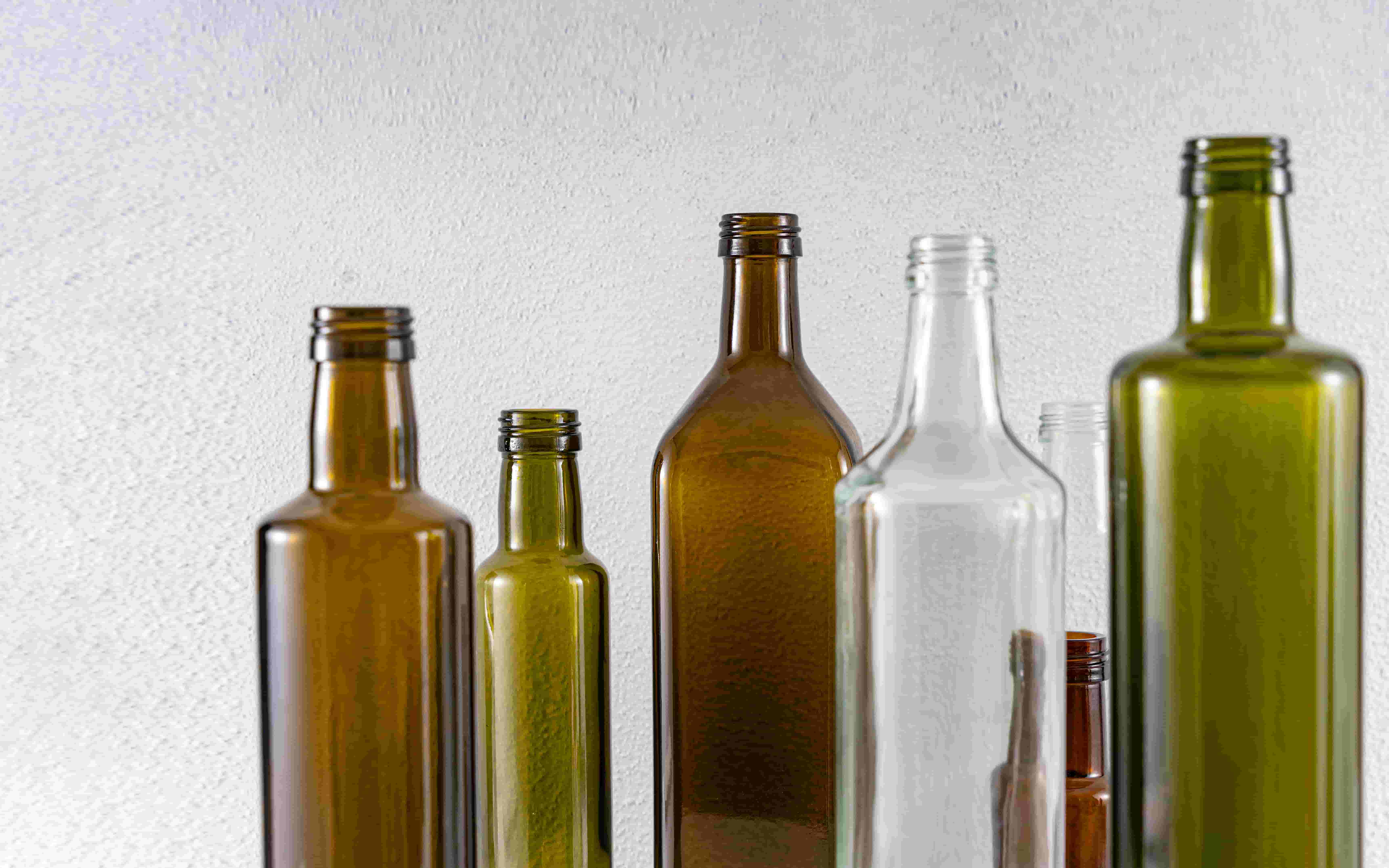 A lineup of raw unbranded glass bottles in square Marasca and round Dorica profiles showing raw material finishes.