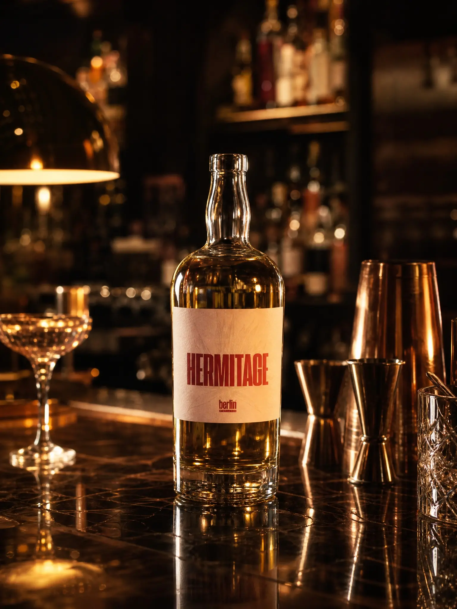 Hermitage spirits bottle filled with golden craft spirit surrounded by bar mixing tools, wholesale empty glass bottles for distilleries Berlin Packaging APAC
