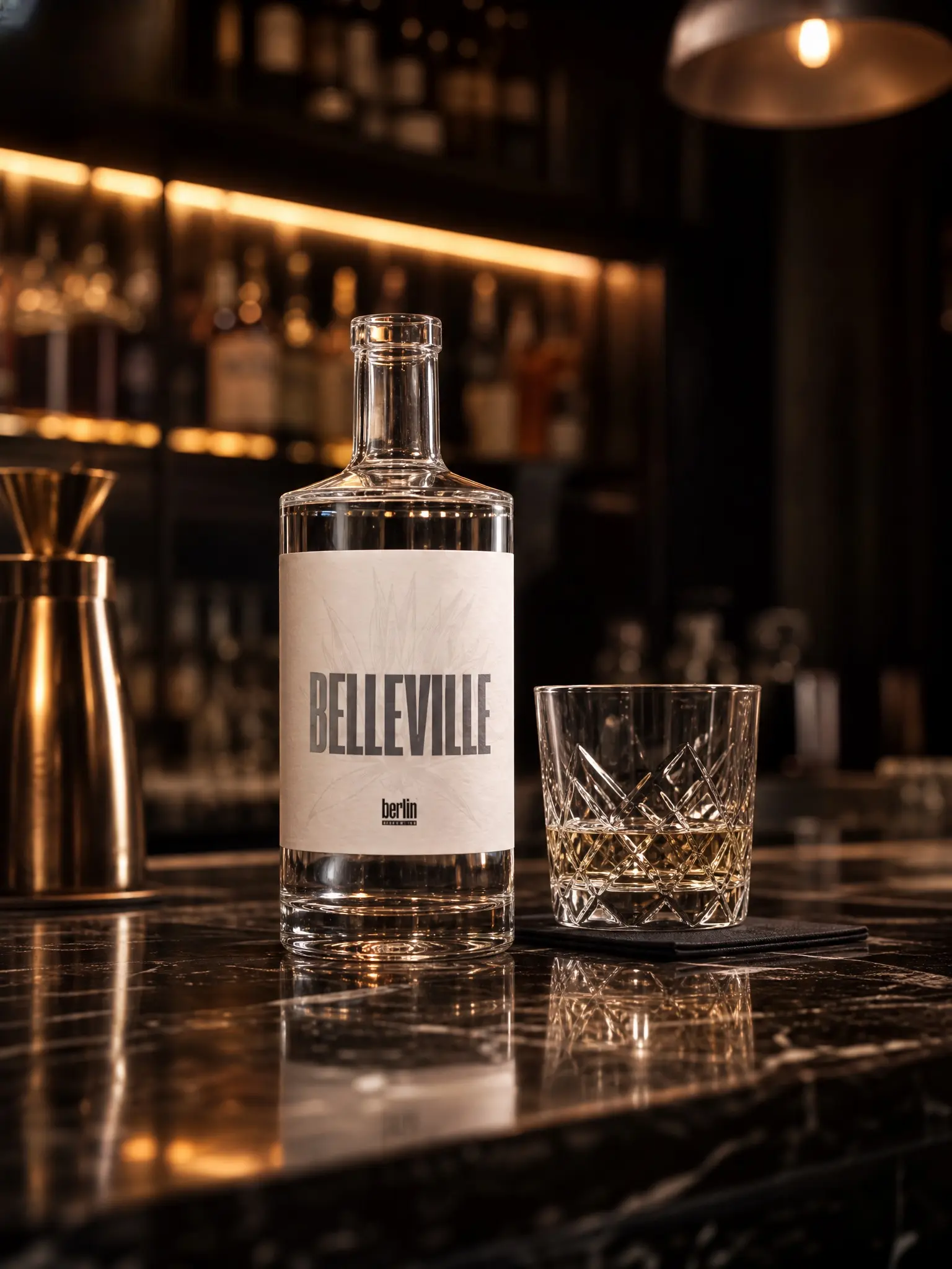 Belleville rectangular flint glass liquor bottle filled with amber spirit next to crystal tumbler on dark marble bar, bulk wholesale bottles for whisky brands Berlin Packaging APAC